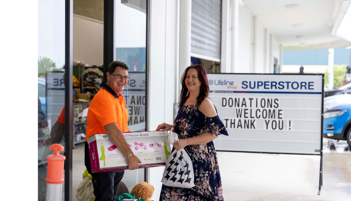 a man and a woman leaving a lifeline shop with some preloved goods.