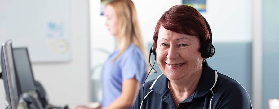 Lady in call centre wearing headset smiling at camera