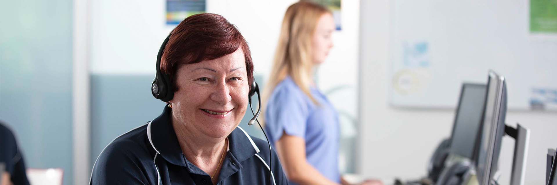 Lady in call centre wearing headset smiling at camera