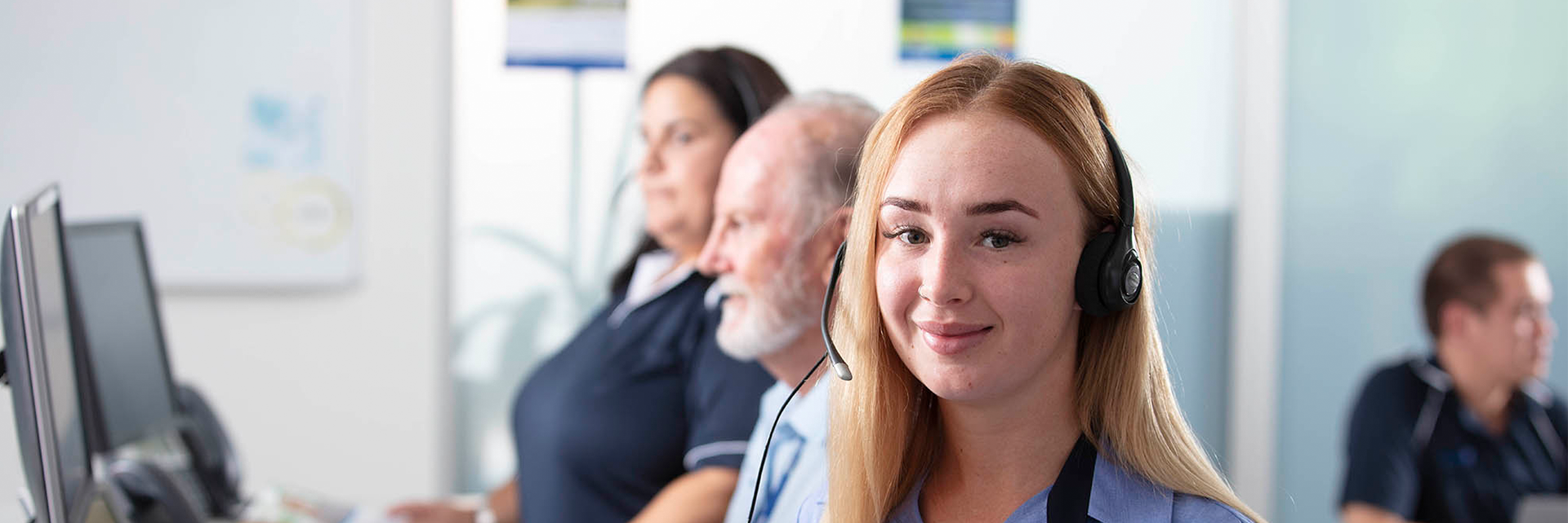 Lady in call centre wearing headset smiling at camera