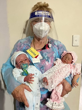 Louisa wearing full PPE and carrying baby dolls
