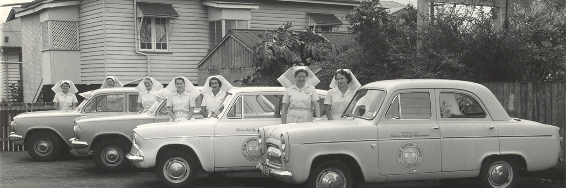 Historical image of Blue Care Nurses standing near their vehicles