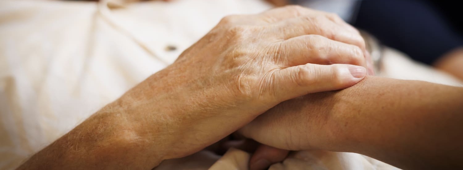 A close up photos of a Blue Care employee holding the hand of an older man