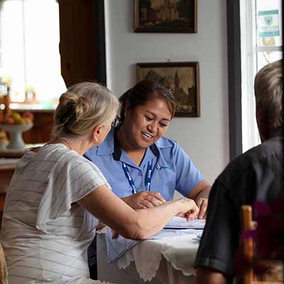 A Blue Care employee reviews documents with an older couple