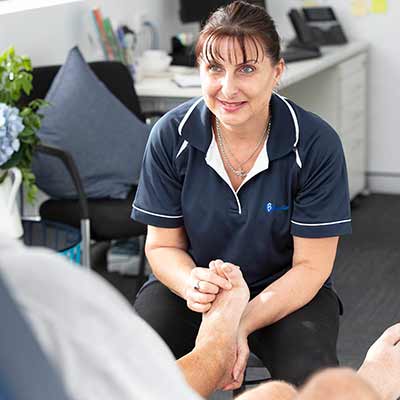 A BlueCare podiatrist performs an assesment on a client's foot