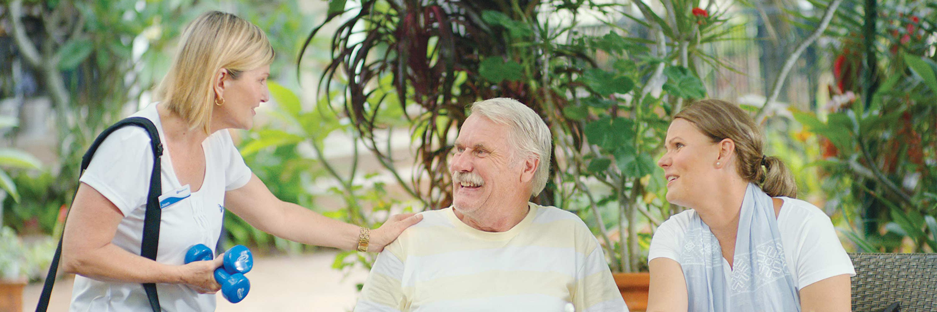 An older man and his daughter smiling at a Blue Care carer