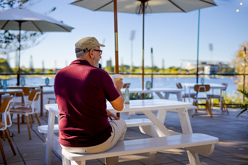 Bokarina Beach Village man seated at a outdoor table near lake kawana