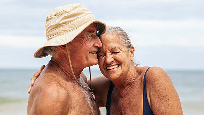 Retirement aged couple cuddling and smiling at the beach