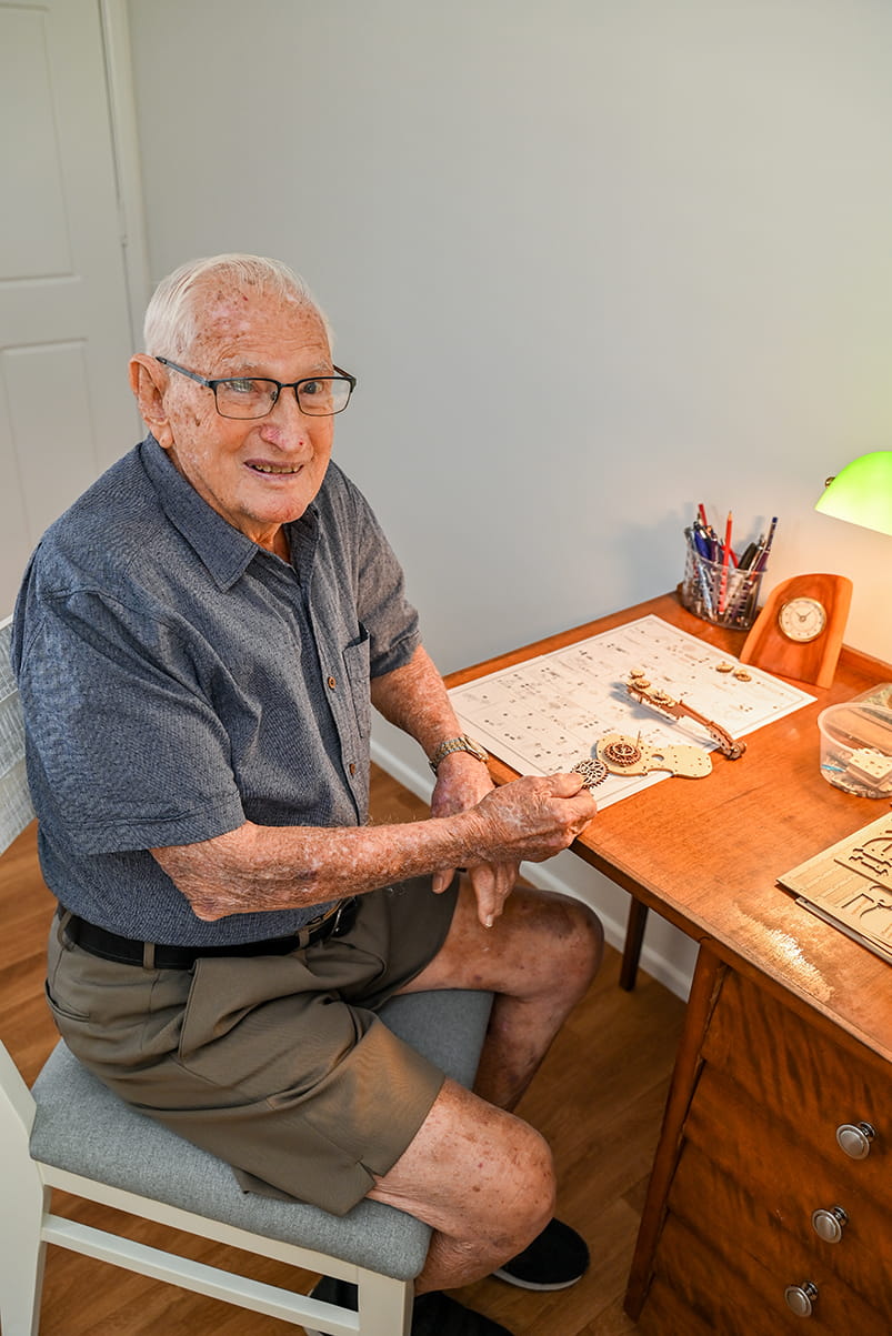 Eric sitting at desk working on cello model