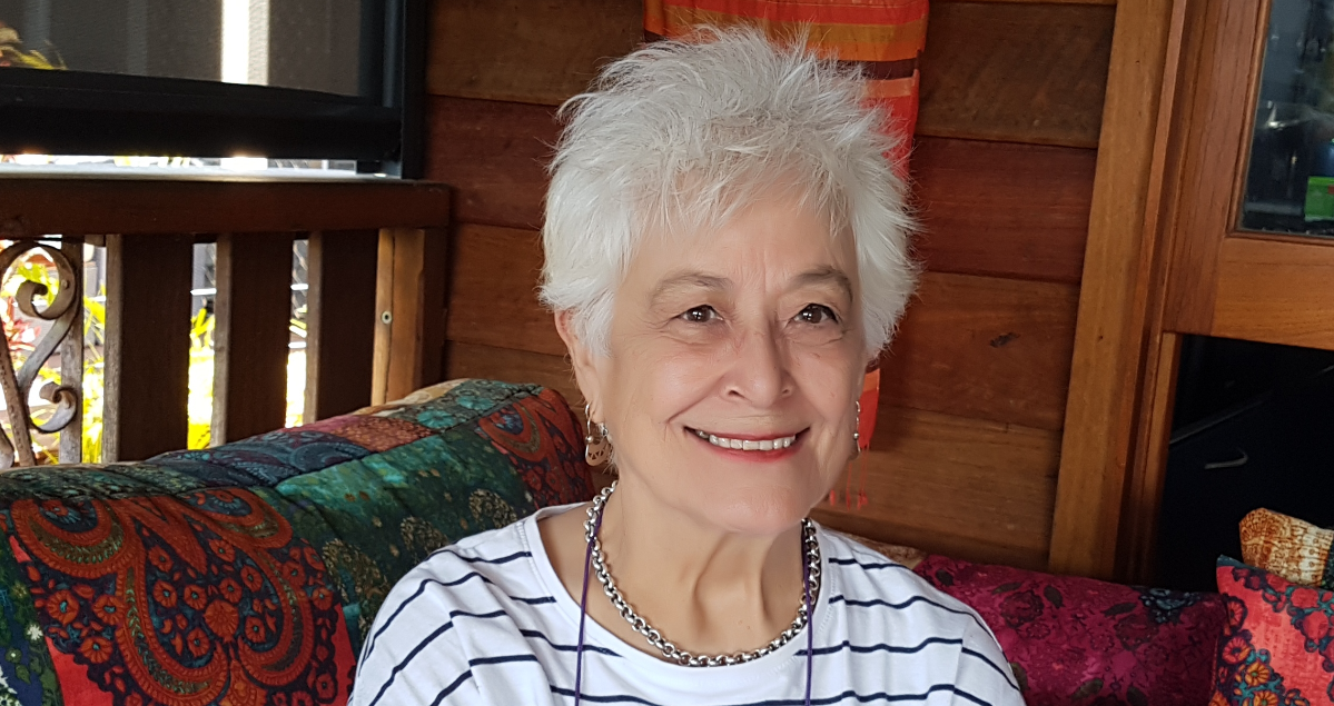 Lesley Kent sits on a colourful couch on her verandah.