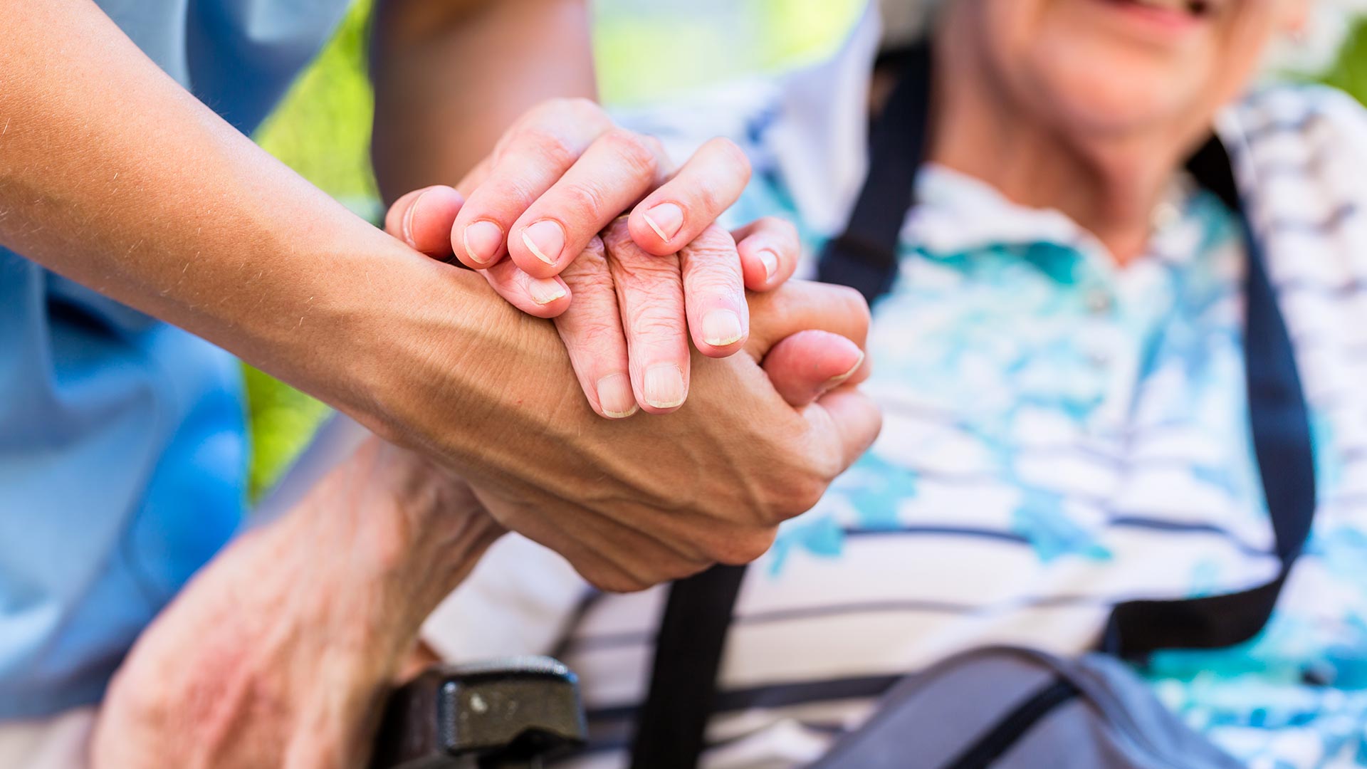 Close up shot of carer and elderly patient holding hands