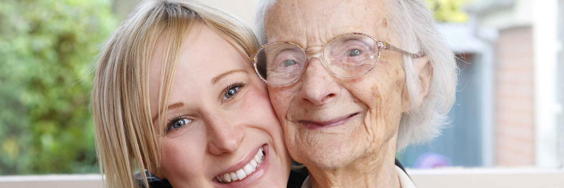 A younger and older lady hugging and smiling at the camera
