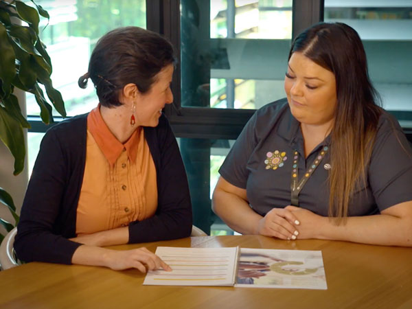Two UnitingCare staff members sitting at a desk reviewing our sustainability report document