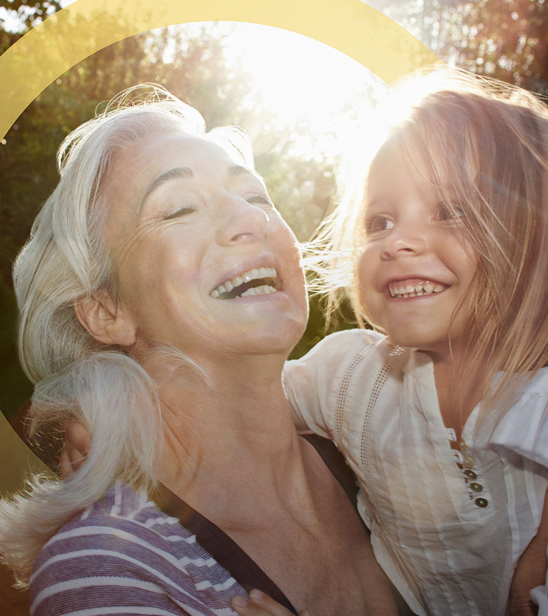 elderly woman smiles while holding a young girl