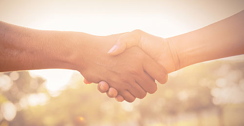 two hands holding with a sunset behind them