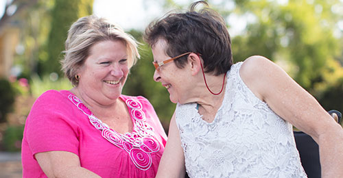 two elderly ladies sitting outdoors smiling