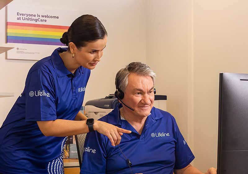 Two Lifeline staff members in uniform chat at a desk.