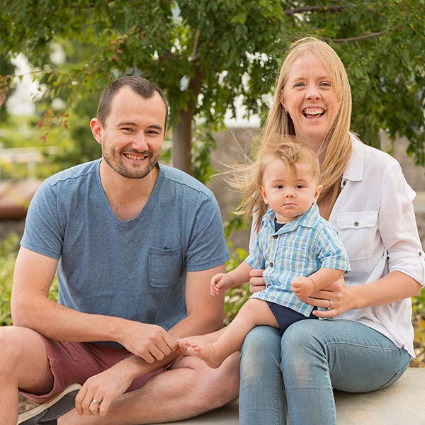 young man and women sitting outside with their infant child