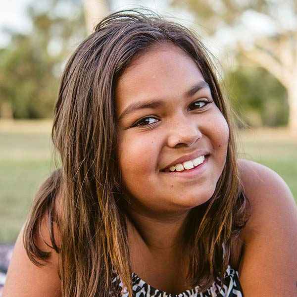 young indigenous girl laying outdoors smiling