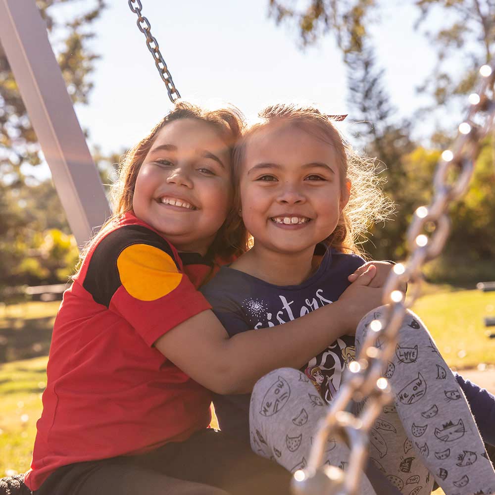 two young indigenous children sitting outdoors smiling