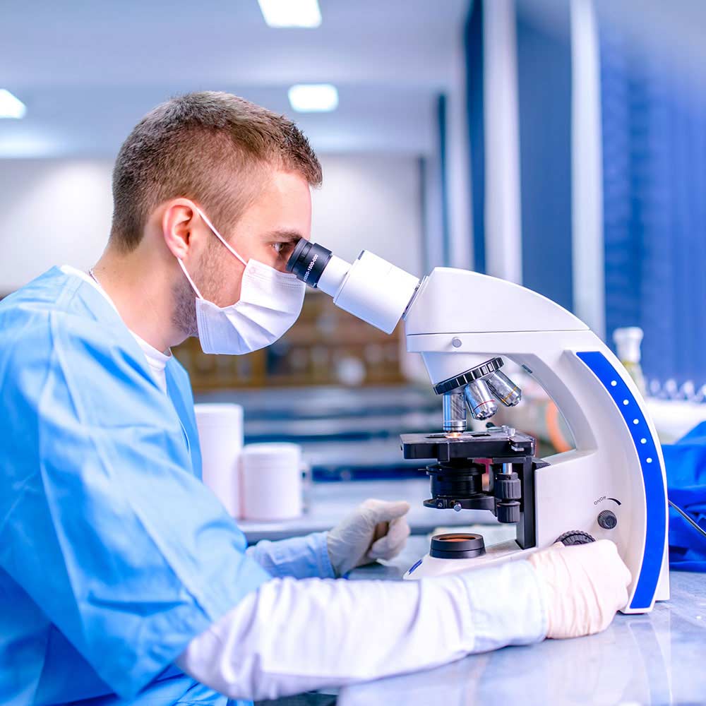 male scientist in a lab looking into a microscope