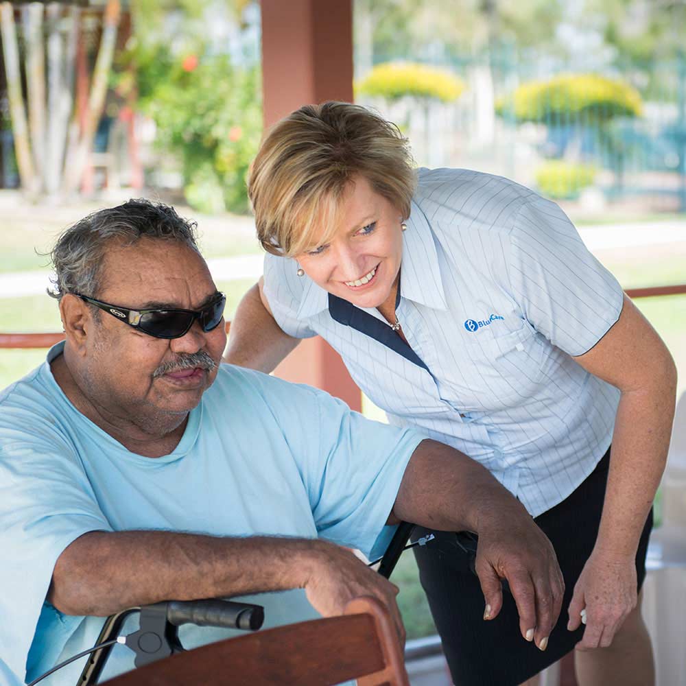 elderly man sitting outside in conversation with a staff member