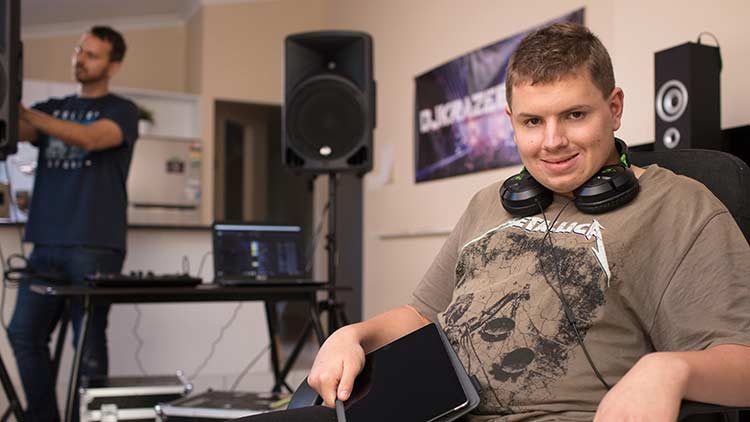 young man in metallica t-shirt sitting in a music studio with headphones around his neck