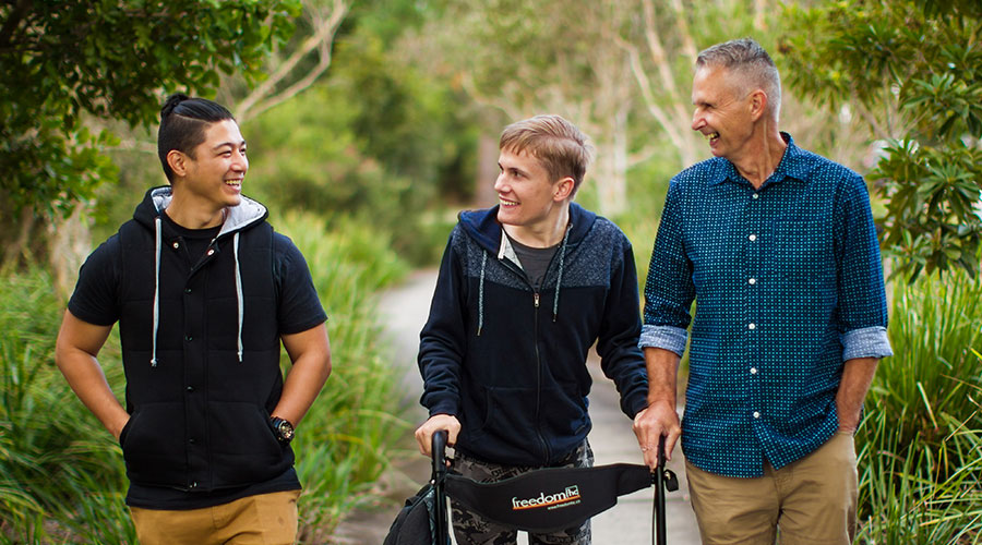 father with a disabled son and another young man walking in the nature