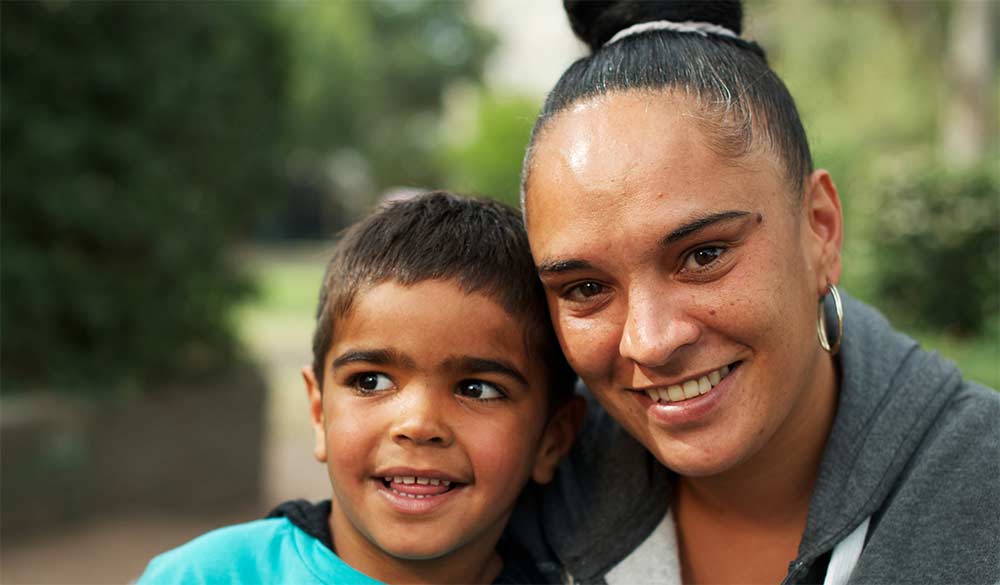 indigenous mother and son sitting outside smiling