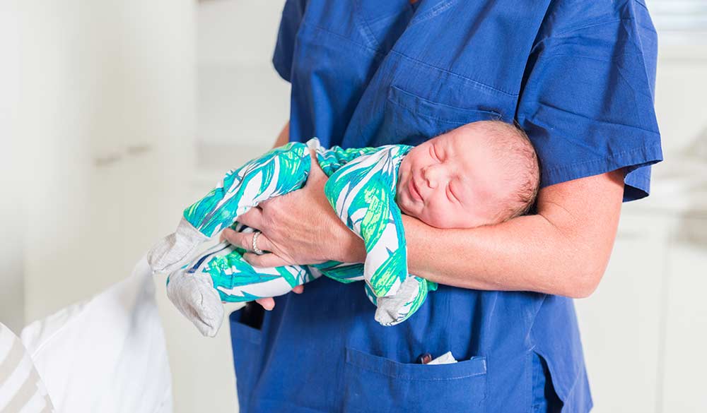 newborn baby in the arms of a nurse