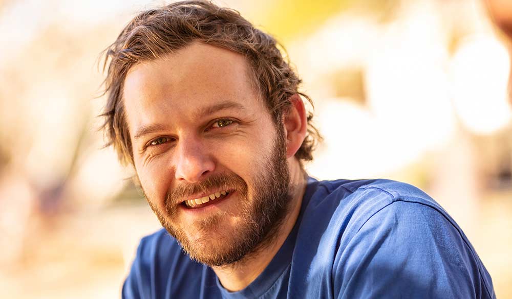 man in a blue shirt sitting outside smiling