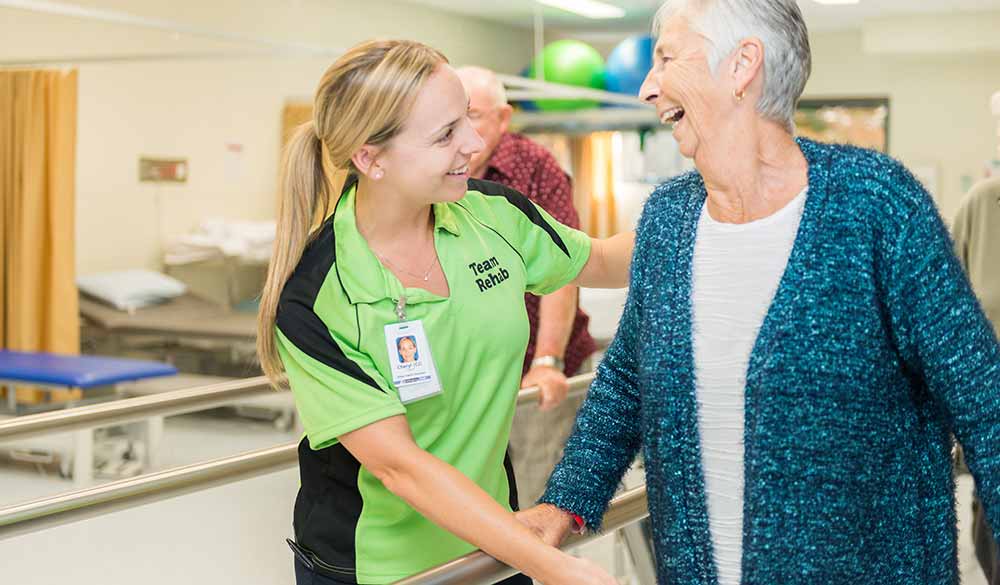 elderly woman assisted inside a hospital by a staff member