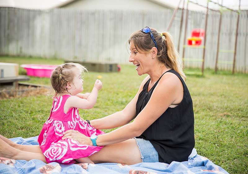 mother sitting outdoors holding her infant daughter