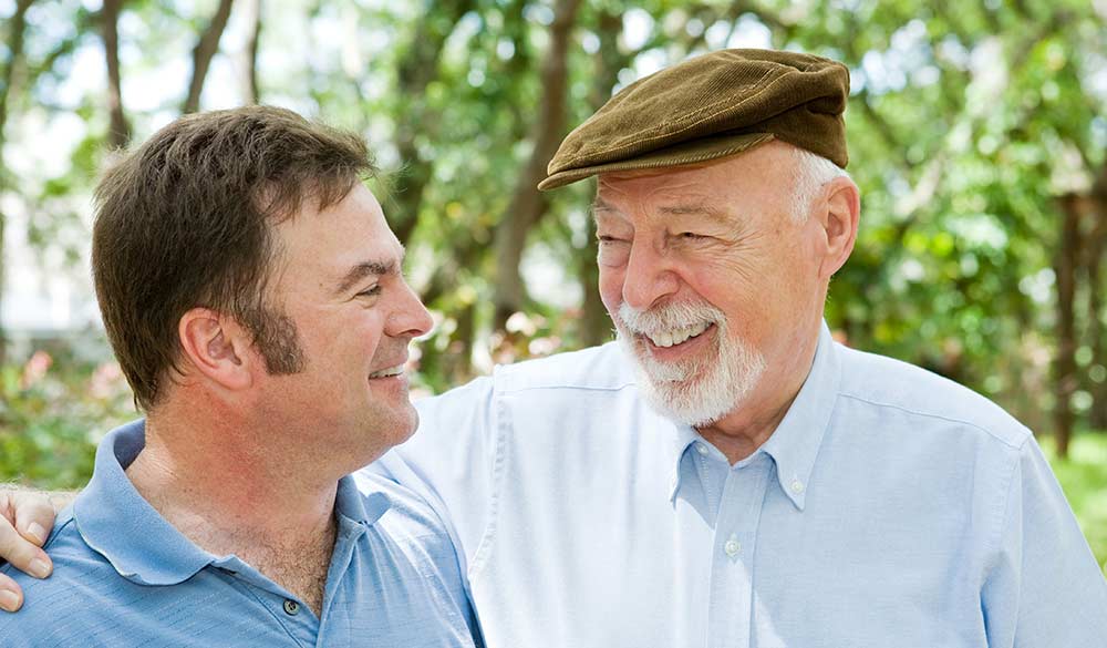 elderly man smiling outside with male staff member