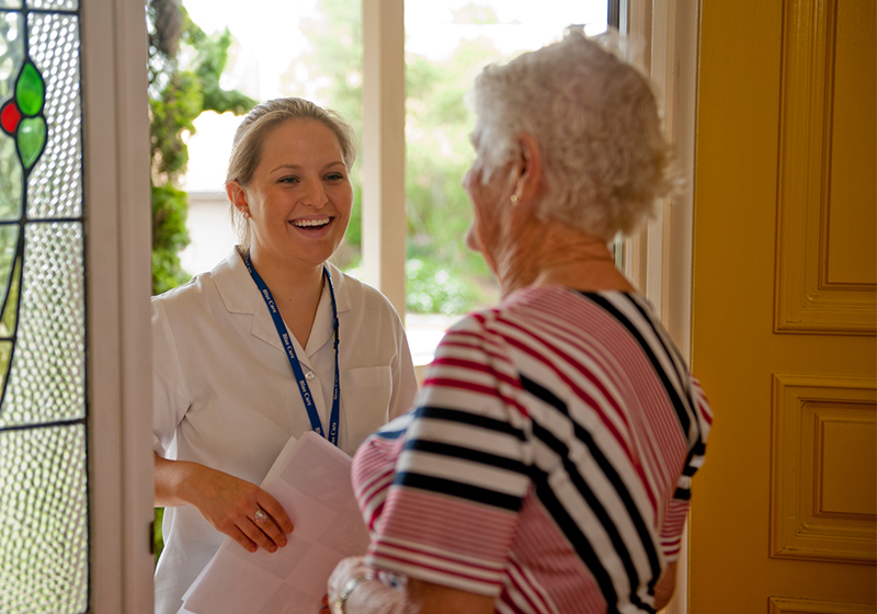 elderly woman greeted at door by staff member