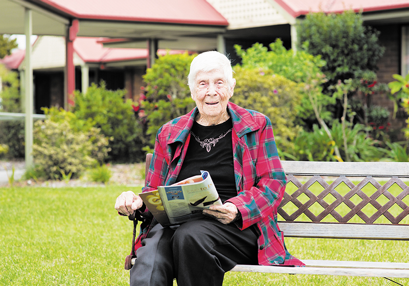 elderly lady sitting on park bench outside