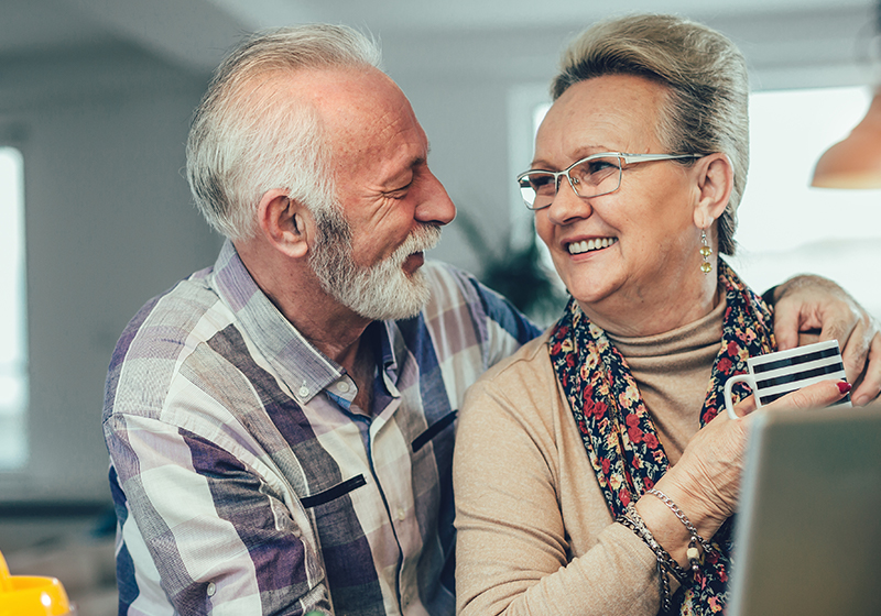 elderly couple embracing in front of a laptop