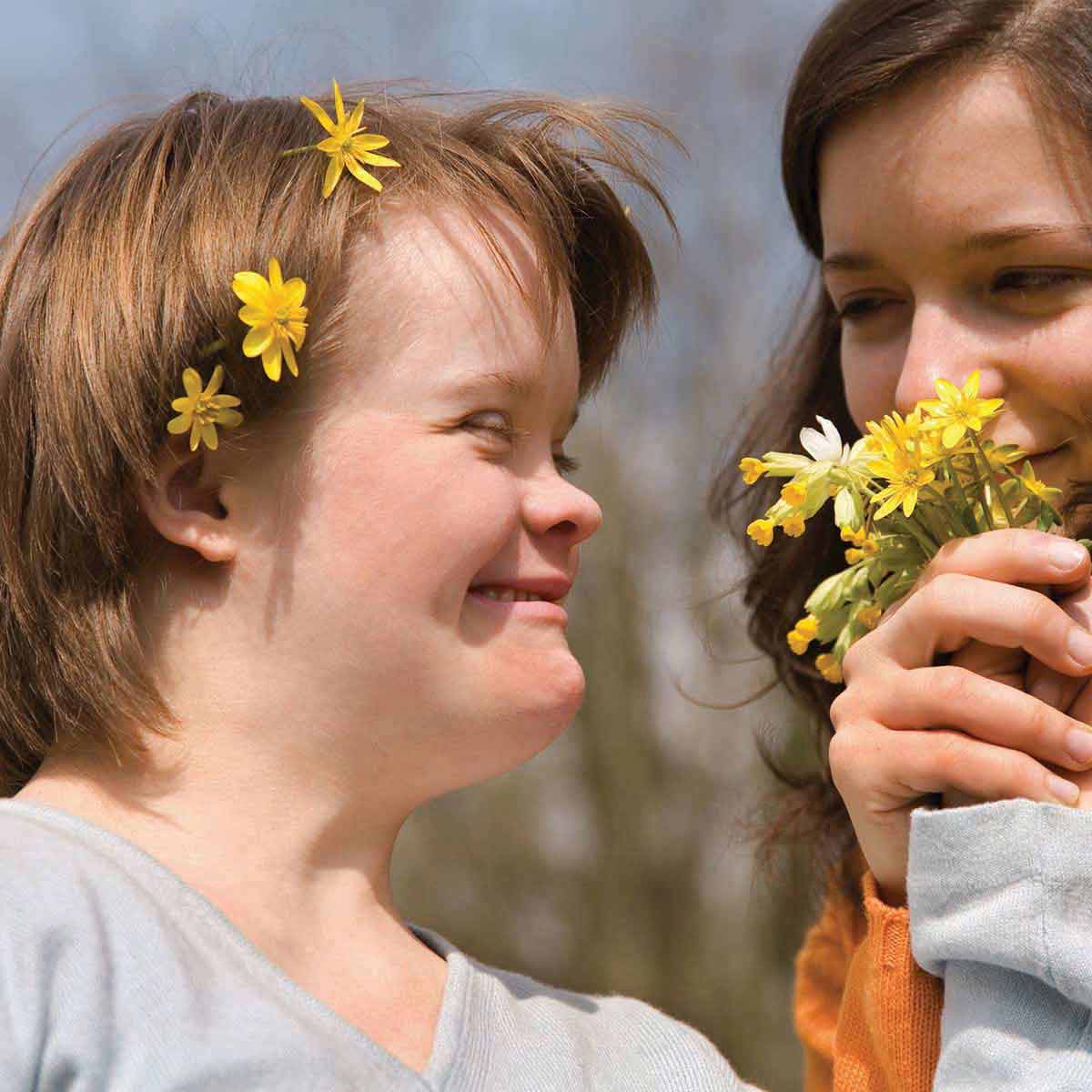 down syndrome girl with flower crown having fun with carer and flowers
