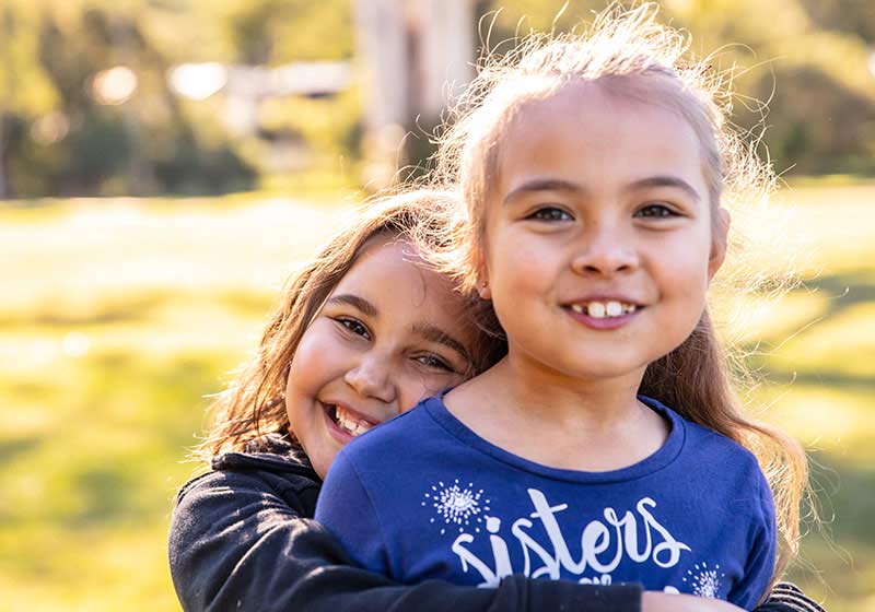 two happy children smiling at camera in the sun