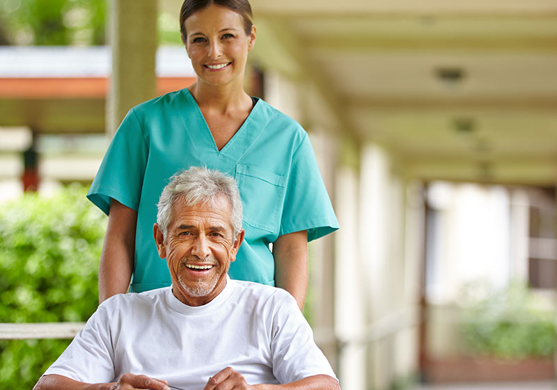 happy old male patient in wheelchair with young pretty nurse