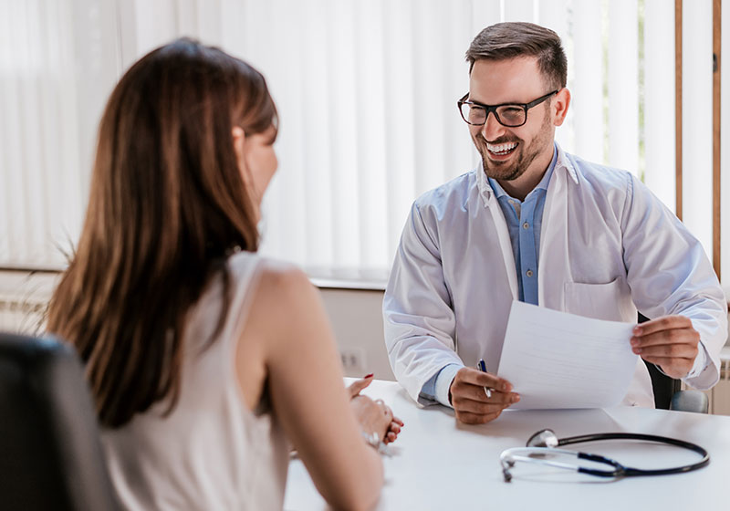 male doctor delivering happy news to woman patient
