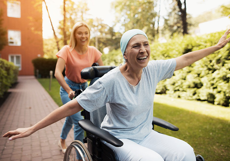 happy cancer patient pushed in wheelchair by daughter