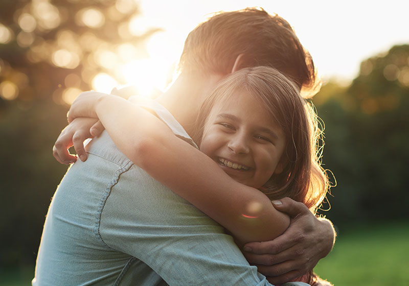 father and daughter embrace in a hug at sunset outside