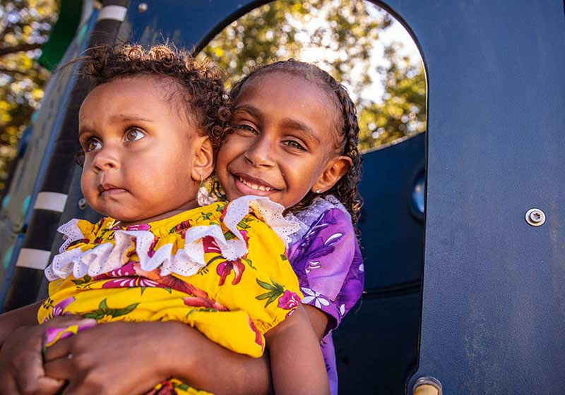 two aboriginal children smiling on a playground