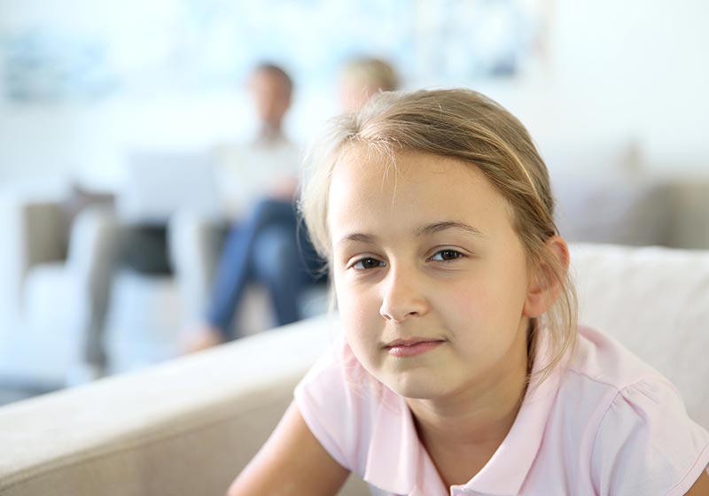 Girl looking at camera with parents in background