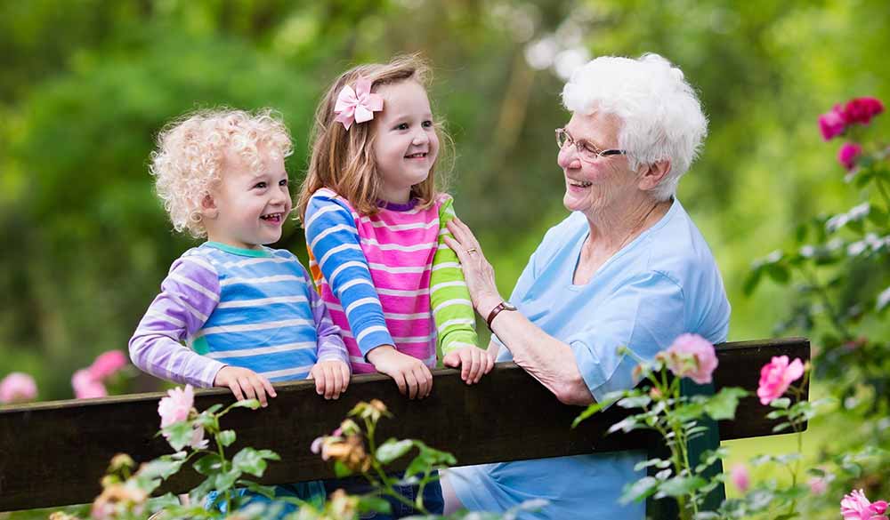 two grand kids playing with grandma in the garden