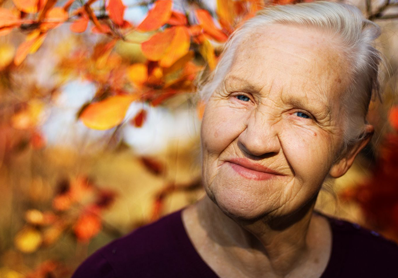 Elderly woman against orange leaves