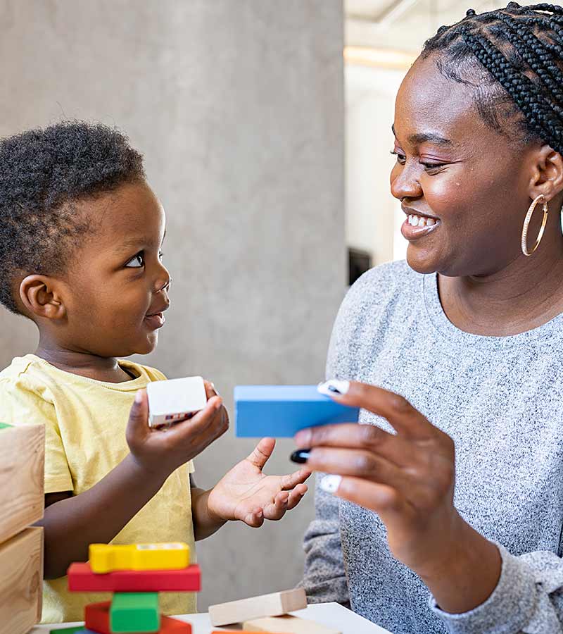 A young boy plays blocks with his mum