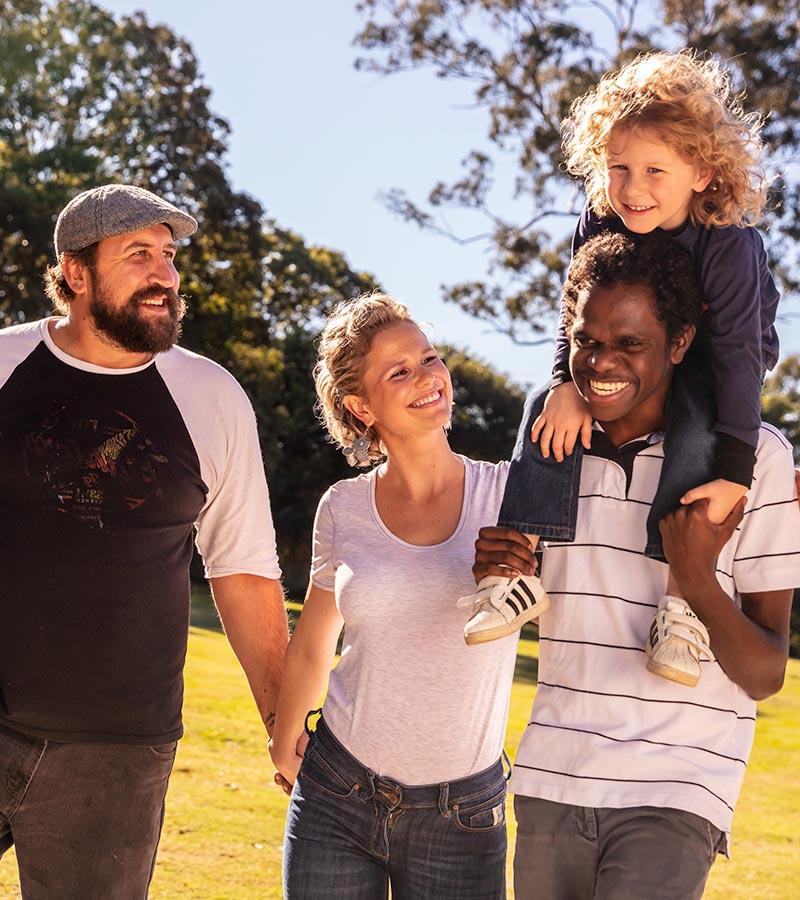 Multicultural family walking together through park and smiling