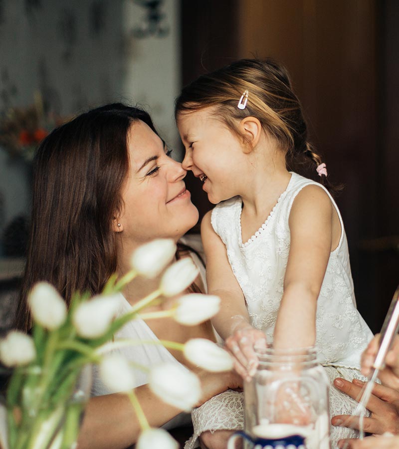 A mother and child bumping noses and smiling at each other